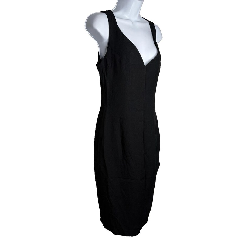 Op de afbeelding: Een zwarte mouwloze jurk met een V-hals. De jurk wordt getoond op een witte mannequin. De jurk heeft een getailleerd silhouet en lijkt gemaakt van een gladde stof. De jurk is knielang.