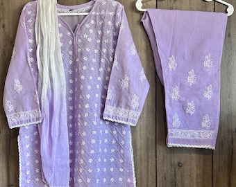 Puede incluir: Un conjunto de kurta y pantalones palazzo de algodón lavanda con bordados blancos. La kurta tiene cuello en V y mangas tres cuartos. Los pantalones palazzo tienen pierna ancha.