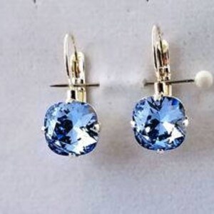 May include: A pair of silver dangle earrings with light blue square-shaped crystal stones.