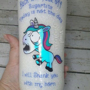 May include: A white glitter tumbler with a cartoon unicorn graphic and the text "Back the fuck off Sugartits today is not the day." The unicorn is blue, teal, and pink, with an angry expression. The text "I will shank you with my horn" is also on the tumbler.