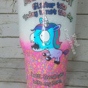 May include: A glitter-covered tumbler with a cartoon unicorn graphic. The tumbler has text that reads "Back the fuck off, Glitter tits, Today is not the day" and "I will shank you with my horn."