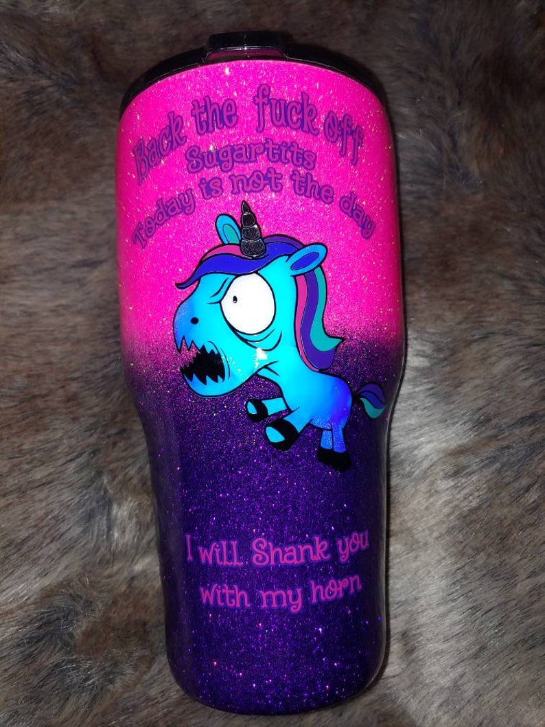 May include: A glittery tumbler with a gradient of pink and purple. It features a cartoon unicorn with the text "Back the fuck off Sugartits today is not the day" and "I will shank you with my horn."
