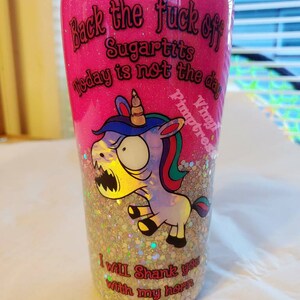 May include: A pink glitter tumbler with the text "Back the fuck off Sugartits Today is not the day" and "I will shank you with my horn." A cartoon unicorn with a menacing expression is also featured.