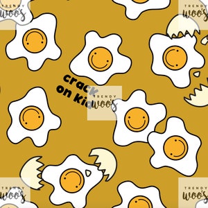 May include: A seamless pattern featuring yellow and white fried eggs with smiling faces on a mustard yellow background. The text "crack on kid woo's" is written in black on a white rectangle.