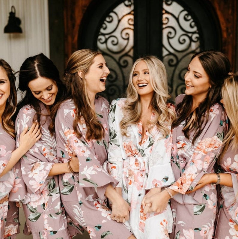 Puede incluir: Un grupo de mujeres con batas de estampado floral en tonos rosa y blanco. Sonr&iacute;en y r&iacute;en juntas, creando un ambiente divertido y festivo.