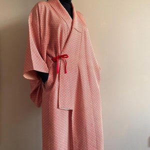 May include: A long, red and white patterned robe with a red sash tied at the waist. The robe has a wide, open collar and long sleeves.