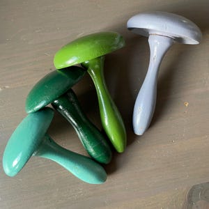 Może przedstawiać: Zestaw trzech ceramicznych kubków z nakrapianym, matowym wykończeniem. Kubki są w odcieniach kremu, jasnoszarym i ciemnoszarym. Każdy kubek ma prosty, minimalistyczny design.