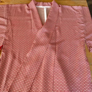 May include: A red and white patterned kimono with a V-neck. The kimono is made of a lightweight fabric and has a relaxed fit.