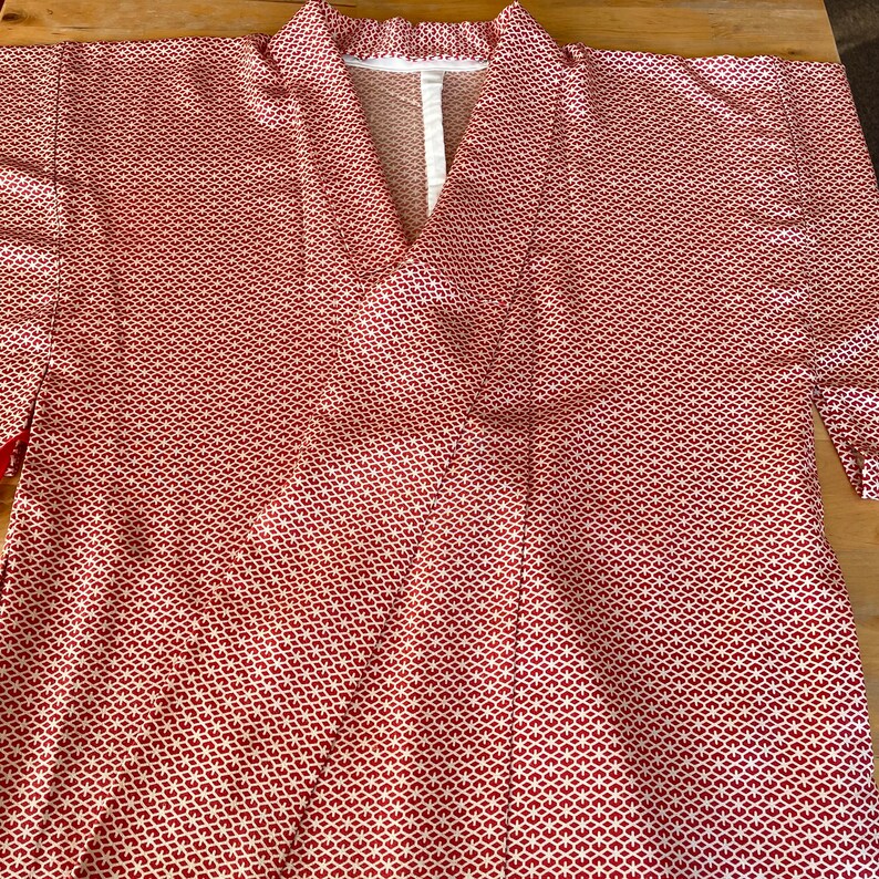 May include: A red and white patterned kimono with a V-neck. The kimono is made of a lightweight fabric and has a relaxed fit.