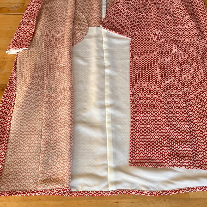May include: A red and white patterned kimono with a white lining. The kimono is open to reveal the lining.