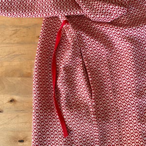 May include: Red fabric with a white geometric pattern and a red ribbon tie.