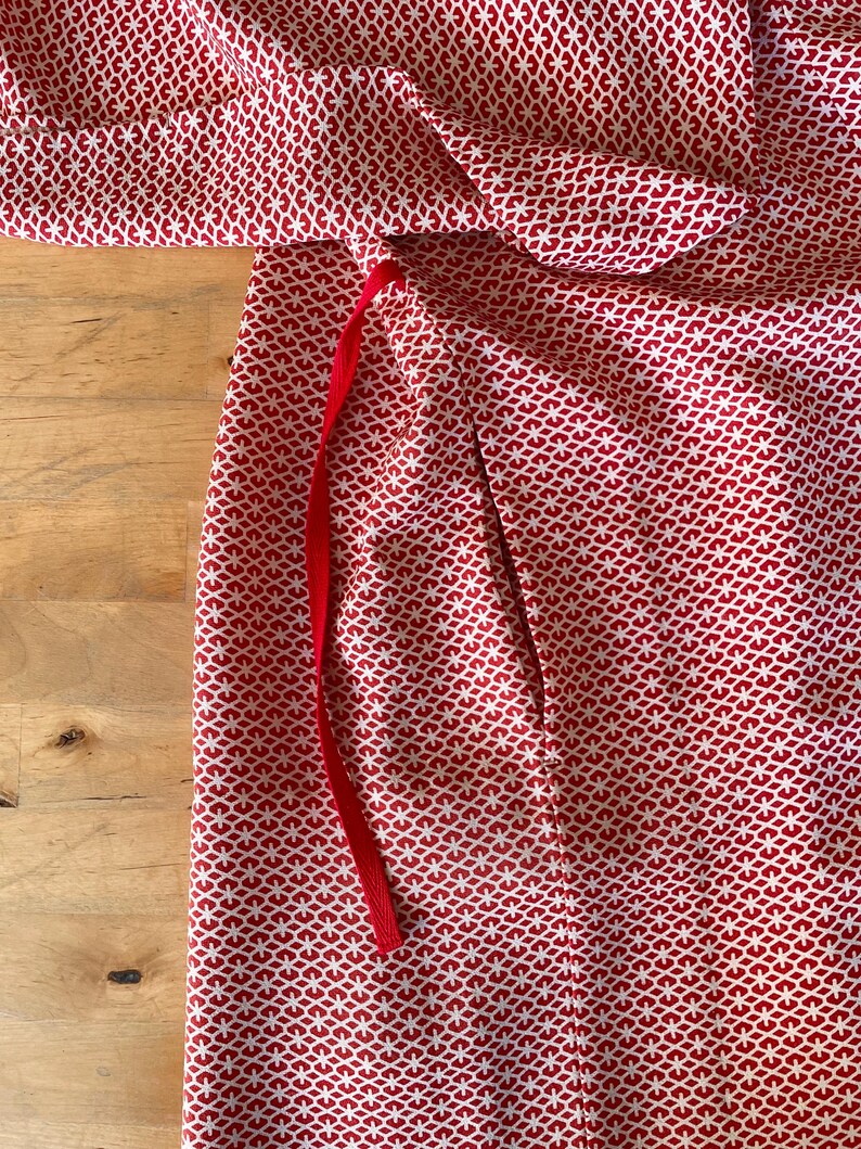 May include: Red fabric with a white geometric pattern and a red ribbon tie.