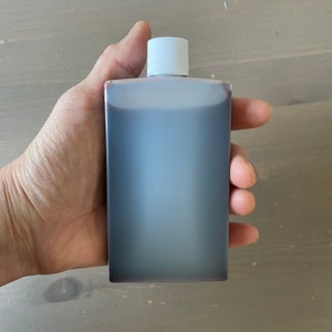 Puede incluir: Una botella de plástico transparente con una tapa blanca llena de un líquido marrón oscuro.