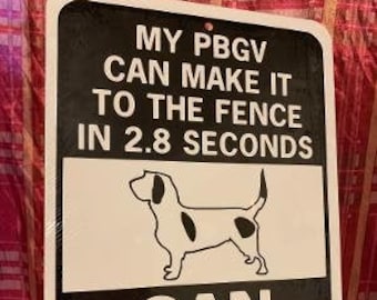 Op de afbeelding: Een zwart-wit bord met de tekst "My PBGV can make it to the fence in 2.8 seconds. Can you?" en een zwart-witte illustratie van een hond.