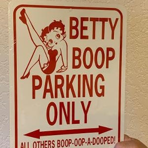 Può includere: Un cartello in metallo bianco con testo rosso che recita "Betty Boop Parking Only" con un'illustrazione di Betty Boop in un vestito rosso. Il cartello include anche il testo "All others boop-oop-a-dooped!"