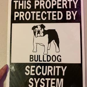 May include: White and black sign with the text "This property protected by Bulldog Security System". A black and white illustration of a bulldog is in the centre of the sign.