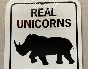 May include: White metal sign with black text and a black silhouette of a rhinoceros. The sign reads "REAL UNICORNS HAVE CURVES".