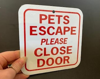 Op de afbeelding: Een wit bord met rode tekst met de tekst "Pets Escape Please Close Door".