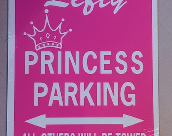 May include: A rectangular pink sign with white text and graphics. The sign features a white crown icon above the text Lefty PRINCESS PARKING. Below this, a white horizontal double-headed arrow sits above the text ALL OTHERS WILL BE TOWED.