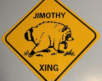 May include: A diamond-shaped yellow road sign with a black border and black text that reads JIMOTHY XING. The center of the sign features a black graphic illustration of a raccoon walking across a small patch of grass.