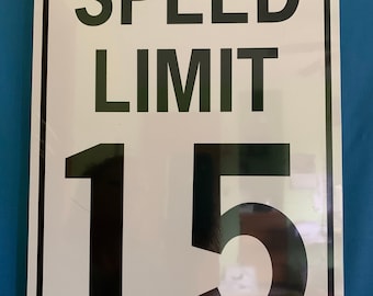 May include: White metal sign with black text and numbers. The sign reads "SPEED LIMIT 15".