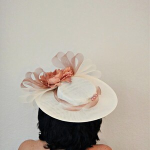 Peut inclure: Un chapeau blanc avec une fleur rose et un ruban rose. Le chapeau est pos&eacute; sur la t&ecirc;te d'une personne.