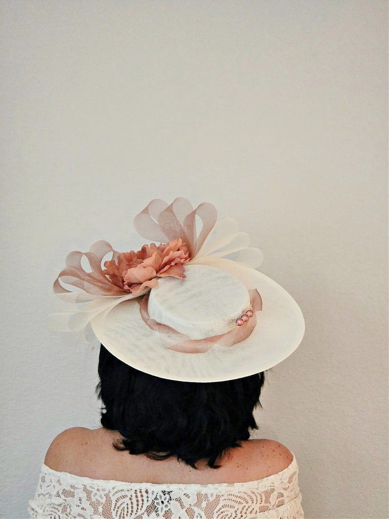Peut inclure: Un chapeau blanc avec une fleur rose et un ruban rose. Le chapeau est pos&eacute; sur la t&ecirc;te d'une personne.