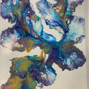 May include: Abstract painting with swirling blue, green, gold, and purple paint on a white canvas. The paint creates a flowing, organic design.