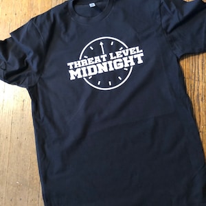May include: Black t-shirt with a white graphic of a clock with the text "Threat Level Midnight" inside.