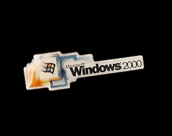May include: A white and blue sticker with the Microsoft Windows 2000 logo. The logo features the classic Windows logo with the text "Microsoft" and "Windows 2000" in black.