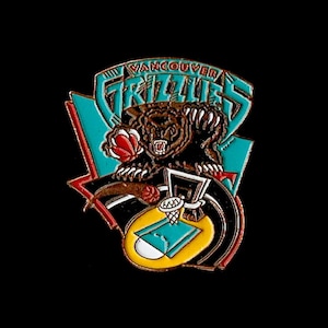 Puede incluir: Un pin de baloncesto vintage de los Vancouver Grizzlies con un oso grizzly de dibujos animados haciendo un mate. El pin es dorado, negro, rojo y turquesa.