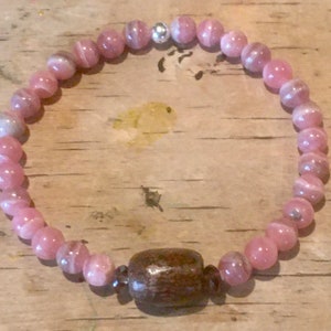 May include: A pink and white gemstone bracelet with a brown wooden bead accent.