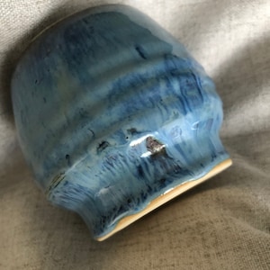 May include: A blue ceramic mug with a white rim and a textured glaze.