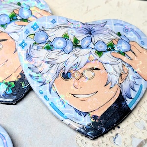 Può includere: Adesivi olografici a forma di cuore con un personaggio anime sorridente con capelli bianchi, una corona di fiori blu e un monocolo. Il personaggio è ambientato su uno sfondo azzurro con un bordo decorativo.