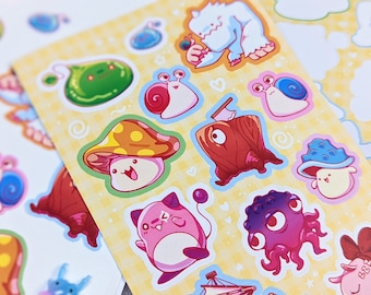 May include: A sheet of colourful stickers featuring various cartoon characters, including a mushroom, a snail, a blob, a fish, and an octopus. The stickers are on a yellow background with white hearts and swirls.
