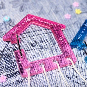 May include: Two pink and blue plastic house-shaped clips with the text "This is a yurt household!!" on the pink clip and "This is a yurt household" on the blue clip.