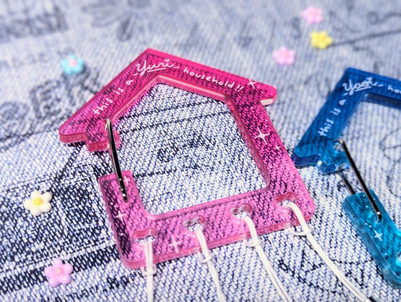 May include: Two pink and blue plastic house-shaped clips with the text "This is a yurt household!!" on the pink clip and "This is a yurt household" on the blue clip.