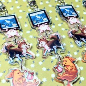 May include: Five colorful keychains featuring cartoon dogs and a small gift box. Each keychain has a blue and white card with the text "Nutzy" on it.