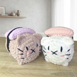 Può includere: Due peluche a forma di gatto sushi realizzati in morbido filato spesso. Un gatto è marrone chiaro con una copertura color lavanda, l'altro è bianco con una copertura rosa pallido. Entrambi hanno occhi, baffi e guance ricamati in nero e rosa.