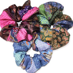 Könnte beinhalten: Ein Set aus drei Keramikbechern mit gesprenkelter, matter Oberfläche. Die Becher sind in Creme-, Hellbraun- und Dunkelbrauntönen gehalten. Jeder Becher hat ein schlichtes Design und einen abgerundeten Henkel.