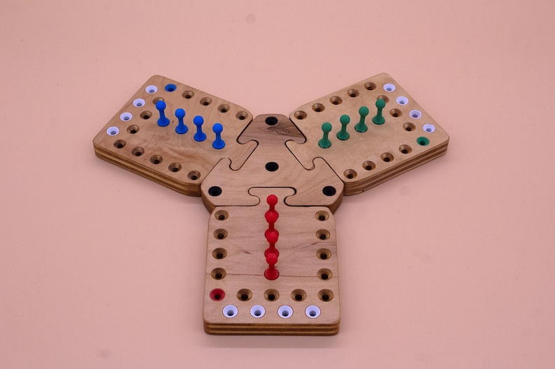 May include: A wooden triangular game board with three sections. Each section has a grid of holes with pegs in them. The pegs are blue, green, and red.