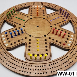 May include: A wooden cribbage board with a circular design and a series of holes for pegs. The board features a natural wood finish and is adorned with pegs in various colors, including green, blue, red, yellow, orange, and purple.