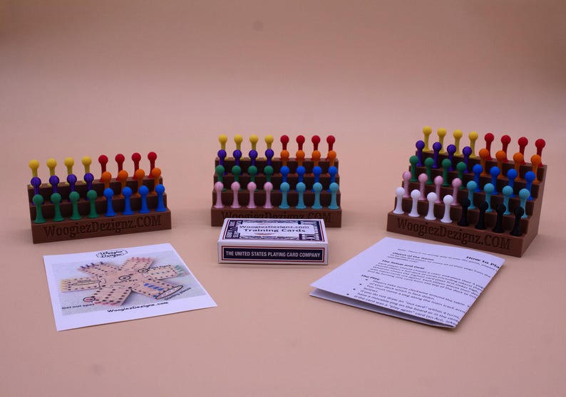 May include: A set of three wooden game boards with colorful pegs. Each board has a different color scheme, with pegs in shades of red, orange, yellow, green, blue, purple, and pink. The boards are labeled with the text "WoogiezDesignz.com".