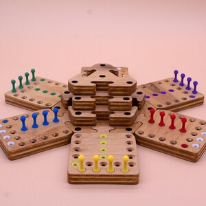 May include: A wooden game board with six sections, each with a different color of pegs. The sections are arranged in a star shape, with a central tower in the middle. The game is called "The Tower of Hanoi".