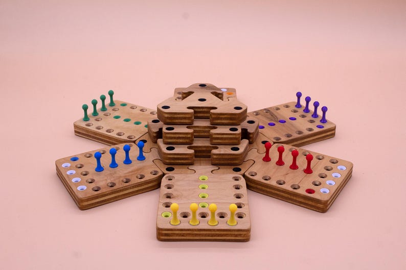 May include: A wooden game board with six sections, each with a different color of pegs. The sections are arranged in a star shape, with a central tower in the middle. The game is called "The Tower of Hanoi".