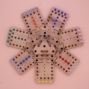 May include: A wooden game board with a star-shaped center and six surrounding pieces. Each piece has a different color of pegs in a line, including orange, green, blue, purple, red, and yellow.
