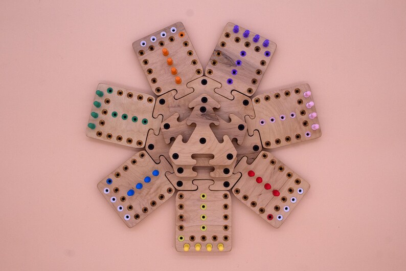 May include: A wooden game board with a star-shaped center and six surrounding pieces. Each piece has a different color of pegs in a line, including orange, green, blue, purple, red, and yellow.