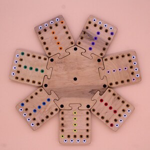 May include: A wooden game board with eight puzzle pieces, each with a different colored pattern of dots. The pieces fit together to form a circle.