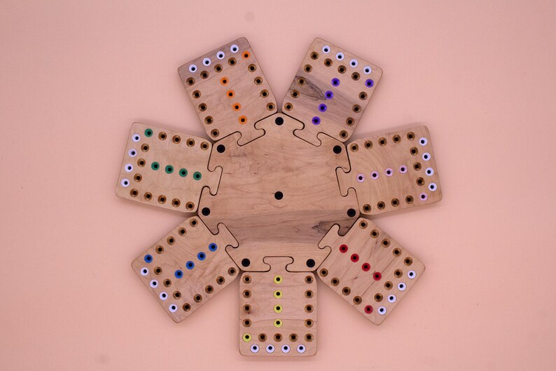 May include: A wooden game board with eight puzzle pieces, each with a different colored pattern of dots. The pieces fit together to form a circle.