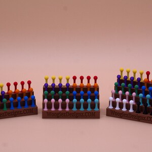 May include: Three wooden display stands with rows of colorful plastic pegs. The stands are labeled "WoogiezDesignz.COM".